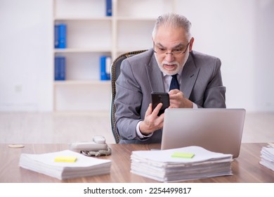 Old male employee and too much work in the office - Shutterstock ID 2254499817