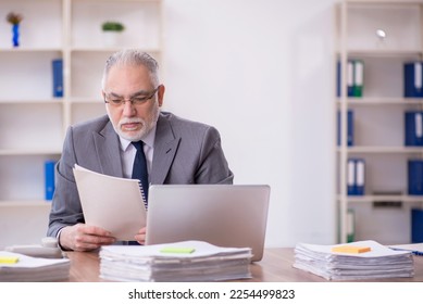 Old male employee and too much work in the office - Shutterstock ID 2254499823