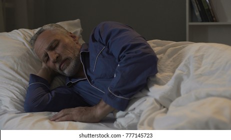 Old male lying in his bed and sleeping, recovery time and healthy sleep, night - Powered by Shutterstock