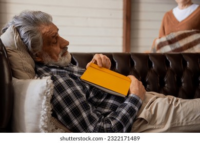 Old male reader taking nap at comfortable sofa at home.Grandpa fell asleep on the couch while reading. - Powered by Shutterstock