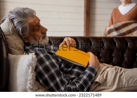 Old male reader taking nap at comfortable sofa at home.Grandpa fell asleep on the couch while reading.