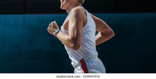 Old Male Runner Running Marathon On Dark Background