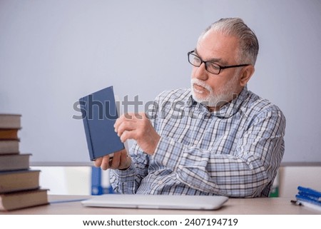 Old male teacher suggesting book