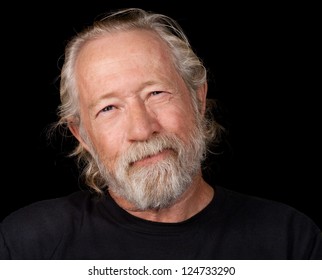 Old man with an amused look on his face isolated against a black back ground