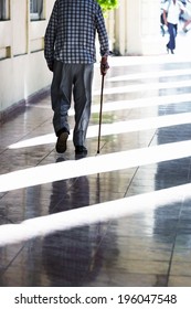 An Old Man With A Cane On The Sidewalk