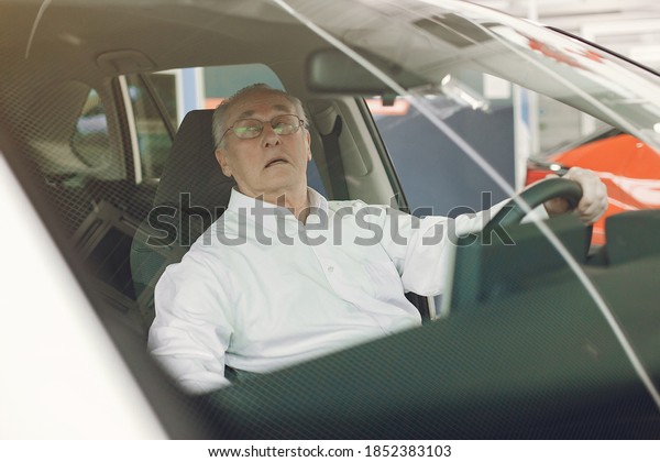 Old man in a car salon. Senior buying the car.\
Grandfather by a car.
