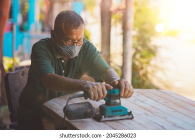 Old man of carpenter working with machine on table
