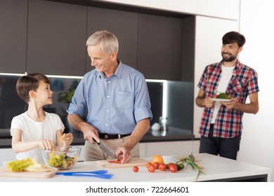 The Old Man Is Cutting Vegetables For A Salad. The Boy Tears The Leaves Of The Salad And The Boy's Father Brought More Vegetables For The Salad On Thanksgiving Day