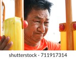 Old man doing an exercise in the park. He try to lift the weight seriously.