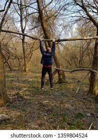 Old man is doing exercises in the forest near the trees