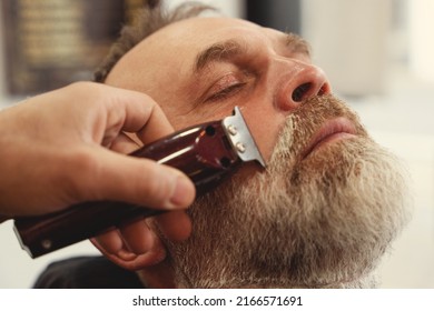 An old man enjoing haircut by a master in a barbershop. An old man gets a stylish haircut
