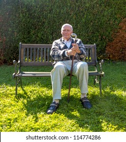 Old Man Enjoys Sitting On A Bench In His Garden