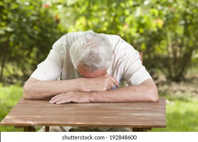 Old man fall asleep with head on table in garden