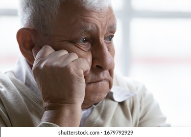 Old man feeling disappointed, lost in sad thoughts close up portrait. Baby boomer generation 80s grandfather suffers from loneliness, chronic or dementia senile diseases, life troubles regrets concept