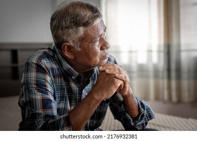 Old Man Feeling Disappointed, Lost In Sad Thoughts And Looking Out The Window. An Elderly Man Sitting On Bedroom Thinking Alone At Home