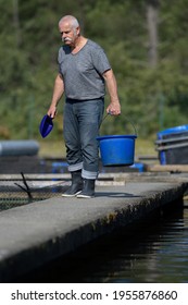 Old Man Fish Farm Worker Carries A Bucket