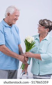 Old Man Giving Flowers To Woman With Walking Frame
