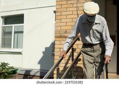 The old man goes down the ramp for the disabled. The pensioner leaves the hospital. An old man holds on to a handrail on the stairs. - Powered by Shutterstock