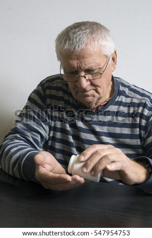 An old man is going to take some pills for his indisposition