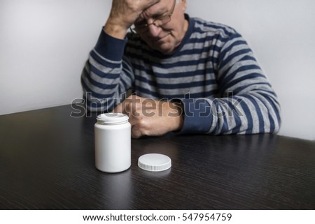 An old man is going to take some pills for his indisposition