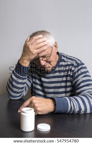 An old man is going to take some pills for his indisposition
