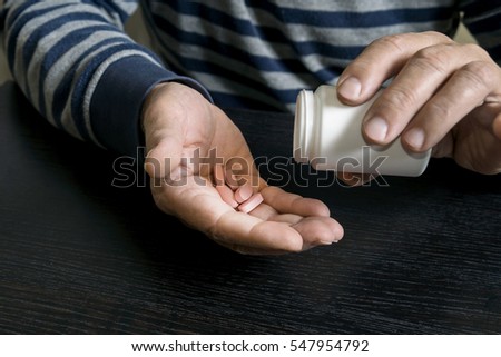 An old man is going to take some pills for his indisposition