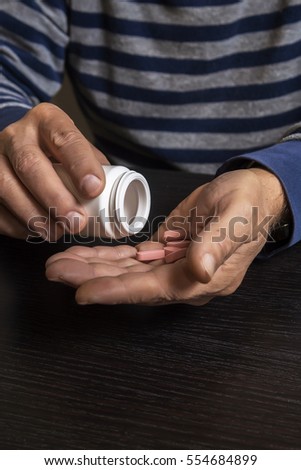 An old man is going to take some pills for his indisposition