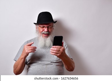 Old Man In A Grey Shirt And Black Fedora Hat Is Angry With Is Smartphone.
Elderly, Retired Gentleman Is Very Mad At This Cell Phone
