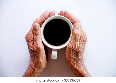 Old Man Hand Holding Cup Of Coffee On White  Background.top View