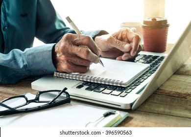 Old Man Hand Writing With A Pen In A Notebook,Handwriting  On Office Wood Table With Laptop Computer