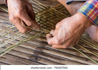 Old man hands manually weaving bamboo.