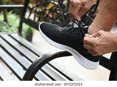 Old Man Hands Tying Shoe For Exercise In Park