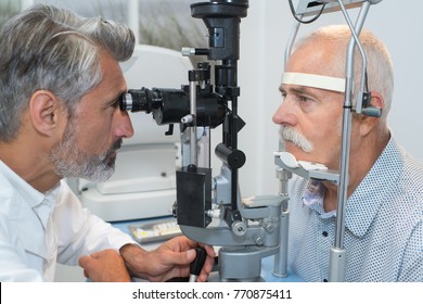 Old Man Having Her Eyes Examined By Eye Doctor