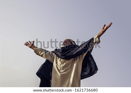 The old man held out his hands to the sky. Freedom. Arab in national dress raises his hands to the sky.