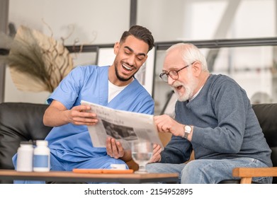 Old man and his caretaker laughing at a news item - Shutterstock ID 2154952895