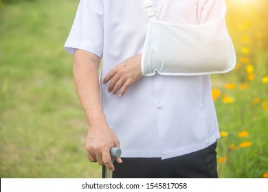 Old Man Holding A Cane Broken Arm After Accident With Wear Arm Splint In The Park