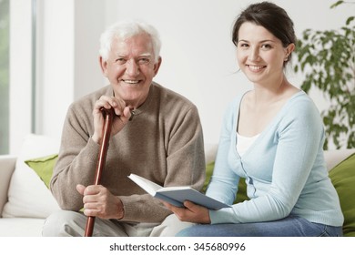 Old Man Holding Cane And Young Woman Reading A Book