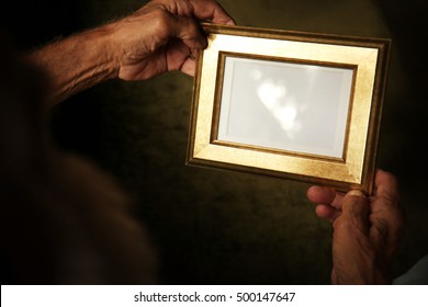 Old Man Holding And Looking At Photo Frame