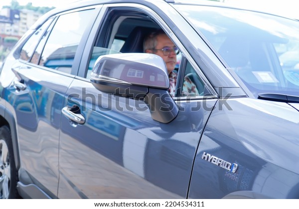 old\
man inside a hybrid car. Automatic and electric\
car.