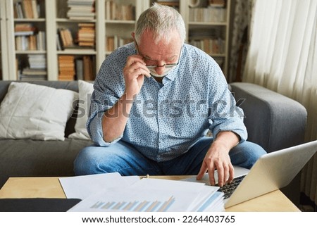 Old man at the laptop computer doing the bookkeeping or preparing the tax return