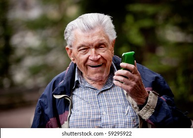 An Old Man Laughing And Smiling With A Cell Phone.