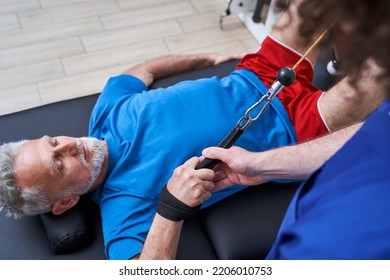 Old man laying and exercising in medical rehabilitation and physical therapy centr - Shutterstock ID 2206010753