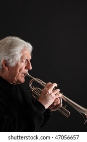 Old Man With Long White Hair Playing A Silver Trumpet Against A Black Background