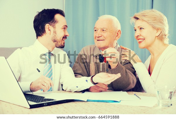Old man and mature woman signing contract car\
lease and hand over keys to manager\
