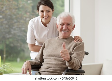 Old man on wheelchair holding thumb up