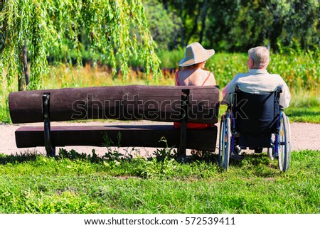 old man on wheelchair with tablet in hands sitting in the park