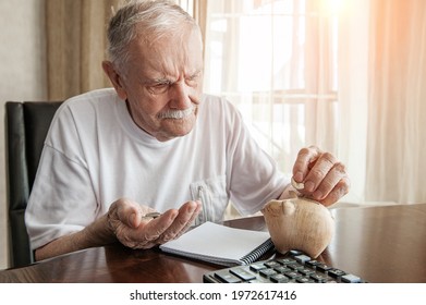 old man in the pandemic counts pennies from the pension fund. Concerned about lockdown, an elderly man puts money in a piggy bank. pensioner calculates the budget of his pension. - Shutterstock ID 1972617416