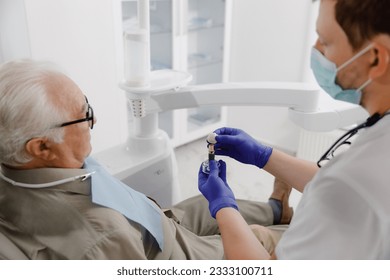 Old man patient have a check appointment at dental clinic the dentist doctor examining the teeth doctor using dental instruments he checking problems with filing - Powered by Shutterstock