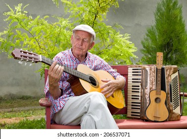 Old Man Playing Acoustic Guitar With Closed Eyes In His Garden