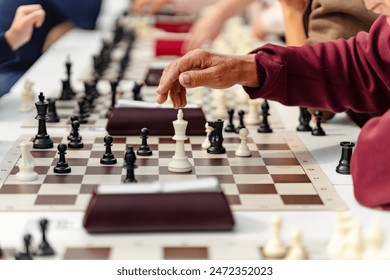 old man playing chess and makes the first move a pawn. Simultaneous game session, a massive collective game of chess. - Powered by Shutterstock